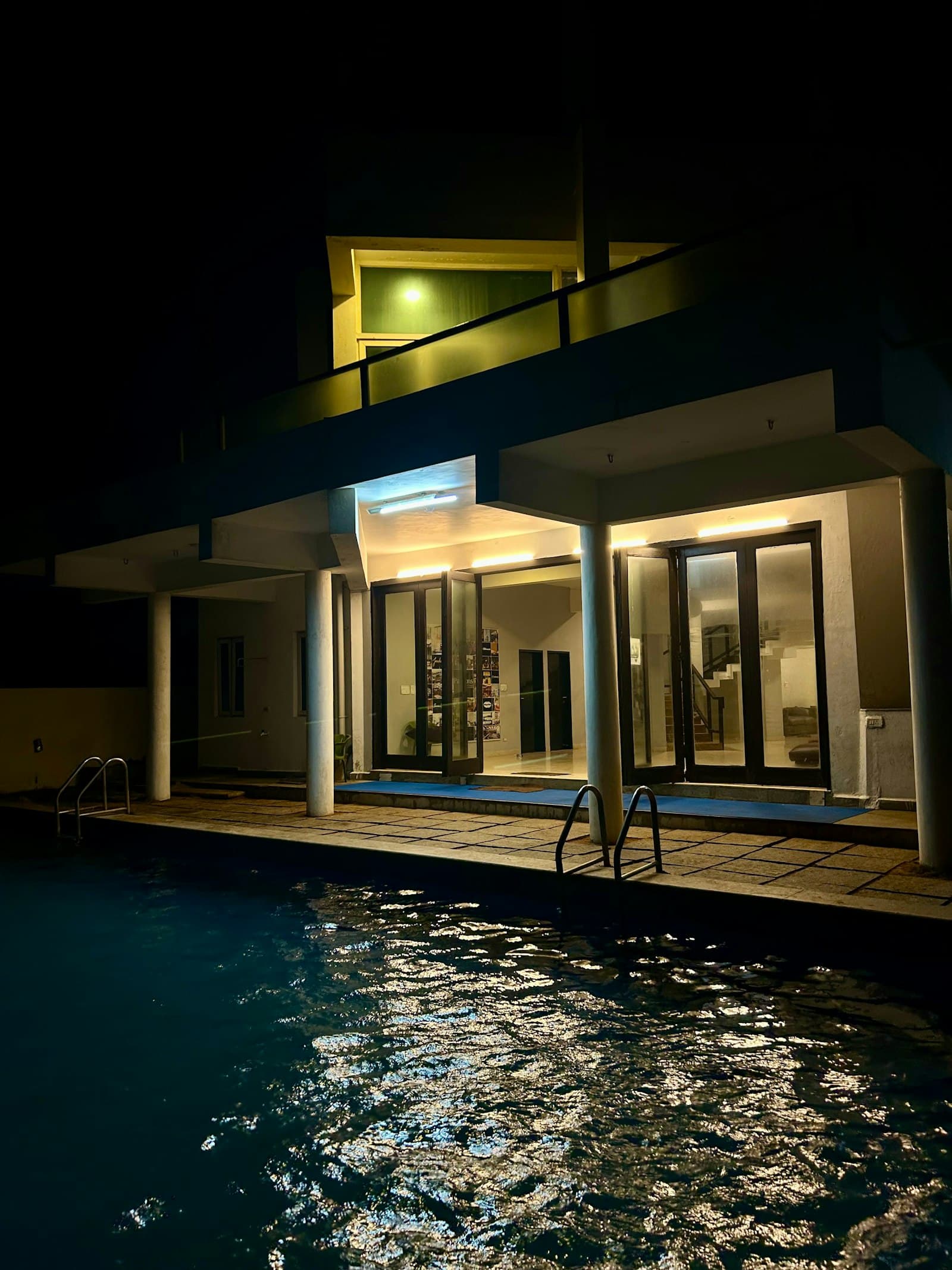 Maison moderne éclairée la nuit au bord d'une piscine